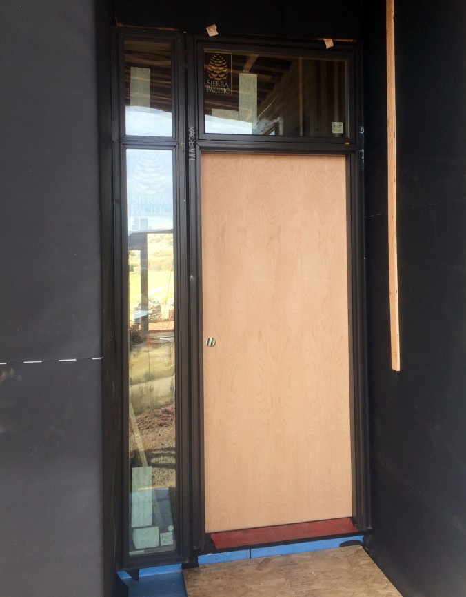 Solid slab wood front door hung on aluminum clad wood frames that match the windows.